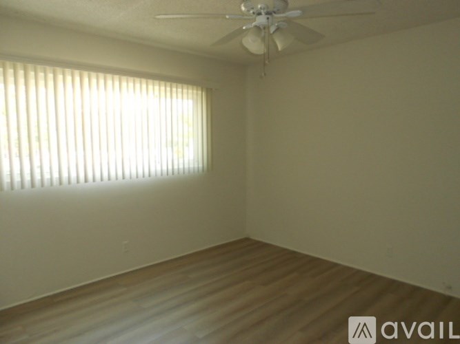 A room with a ceiling fan and a window with blinds.