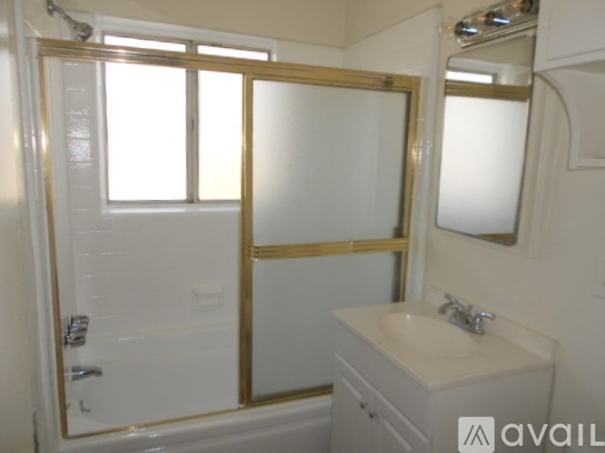 A bathroom with a sink, mirror, and shower.