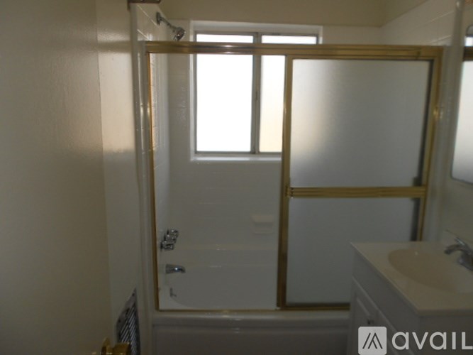 A bathroom with a white tub and sink, and a window with blinds.