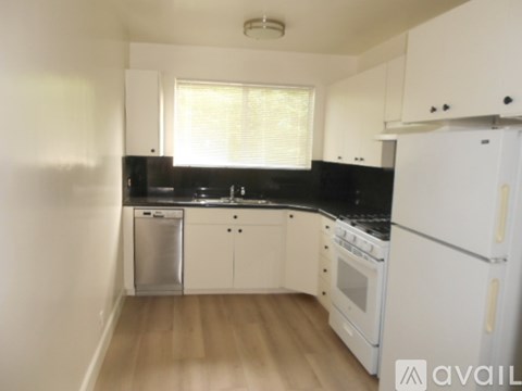 A kitchen with white cabinets and black countertops.