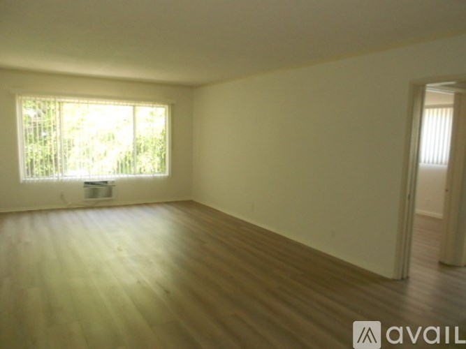 A room with wooden flooring and a window letting in natural light.