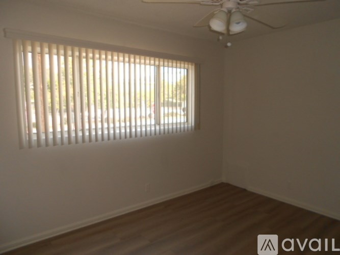 A room with a ceiling fan and a window with blinds.