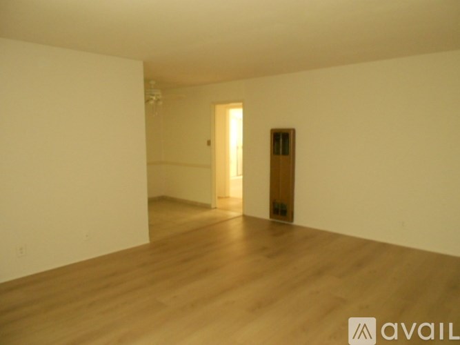 A room with wooden floors and a door in the background.
