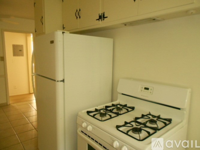 A white gas stove in a kitchen with a white refrigerator.