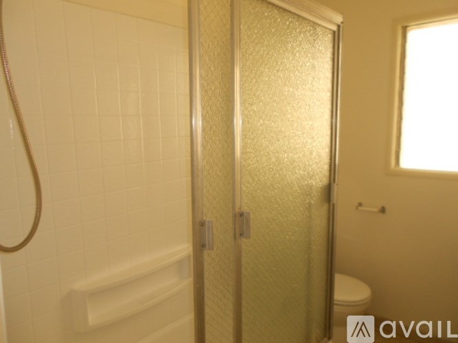 A bathroom with a shower, toilet, and a glass door.