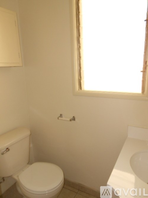 A white toilet sits next to a white sink in a bathroom.