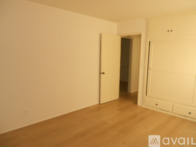 A room with a white door and a wooden floor.