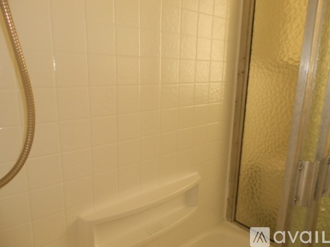 A bathroom with a white tiled shower and a glass door.