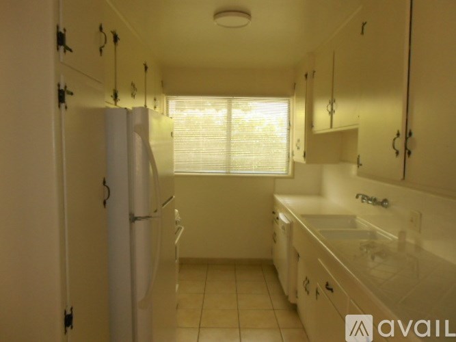 A kitchen with white cabinets and a white fridge.