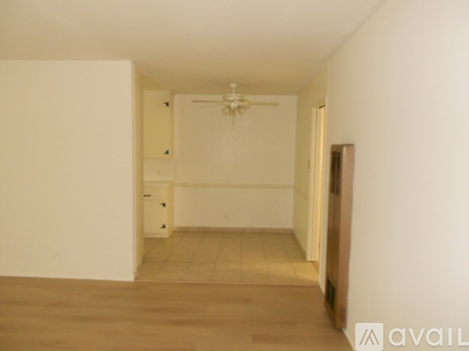 A room with a ceiling fan and wooden flooring.