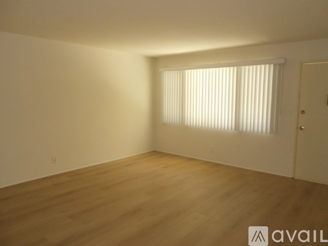 A room with wooden flooring and a window with blinds.