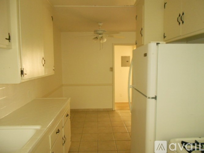 A kitchen with white cabinets and a white refrigerator.