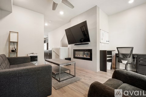 A modern living room with a grey couch and a fireplace.