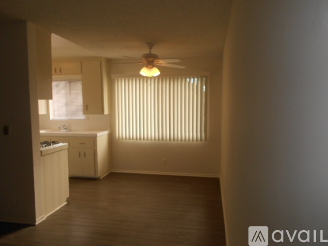 A room with a ceiling fan and a window with blinds.