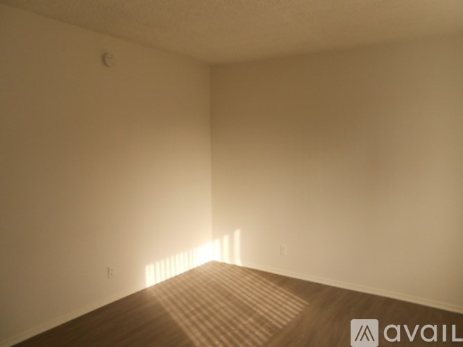 A room with wooden flooring and a wall with a small hole in it.