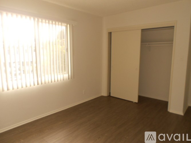 A room with wooden floors and a window with blinds.