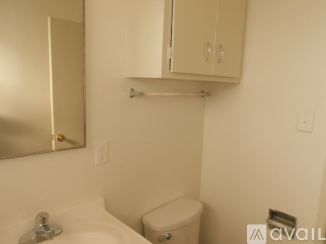 A bathroom with a toilet, sink, and mirror.