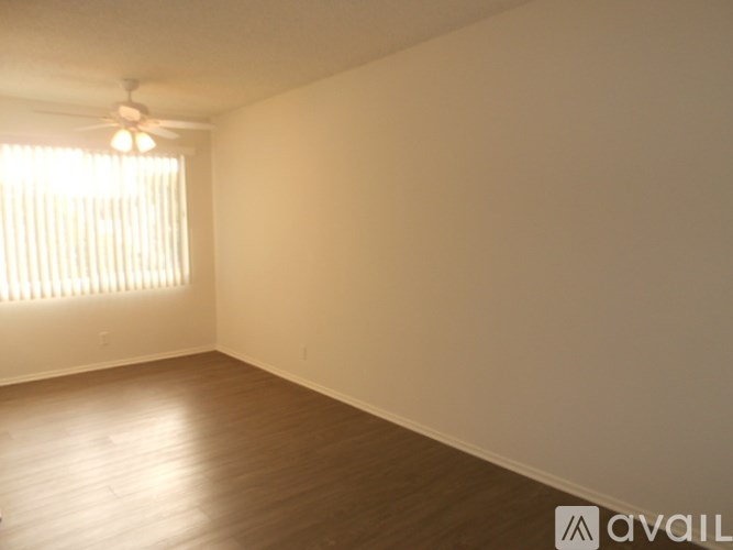 A room with wooden flooring and a window with blinds.