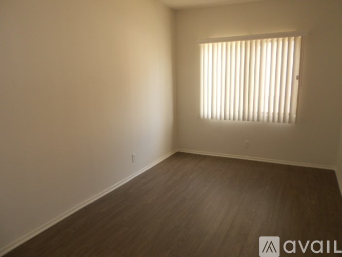 A room with wooden flooring and a window with blinds.