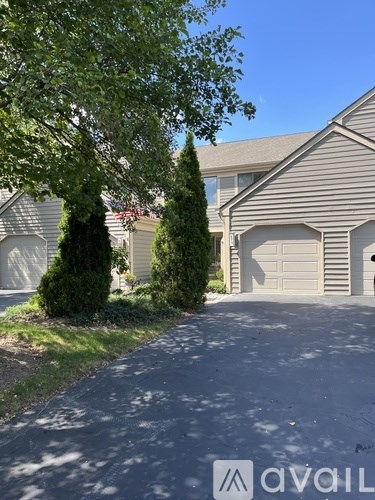 A house with a driveway and a tree in front of it.