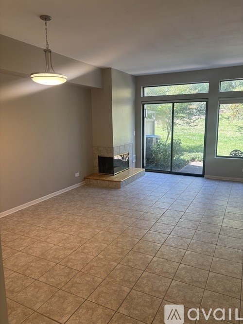 A room with tiled flooring and a sliding glass door leading to a garden.