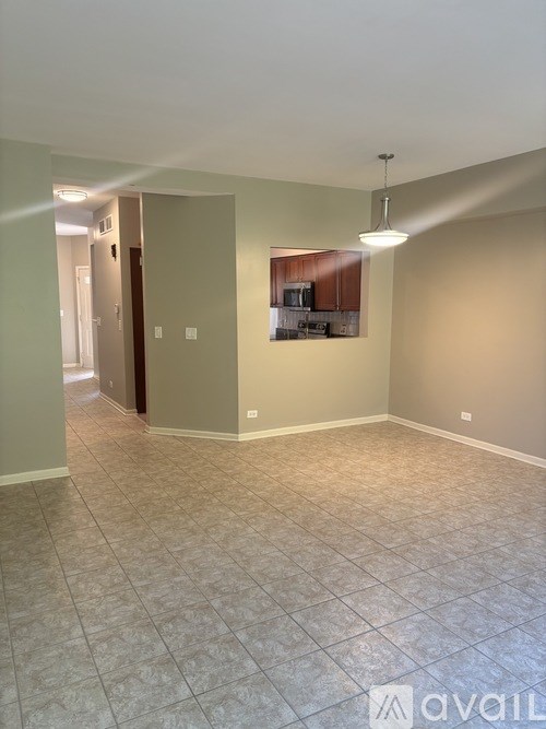 A room with tile flooring and a kitchenette in the background.
