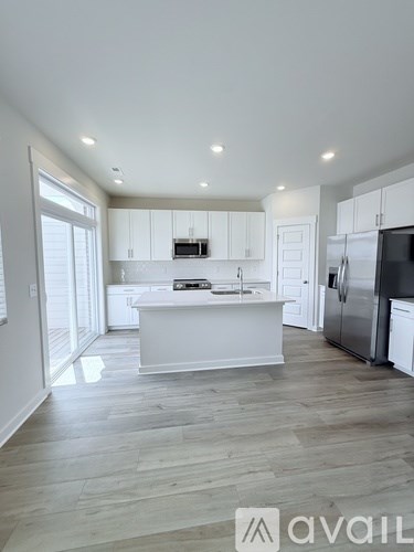 A modern kitchen with white cabinets and a wooden floor.