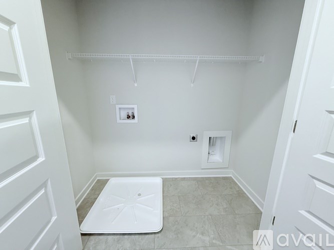 A white bathroom with a white door and a white mat on the floor.