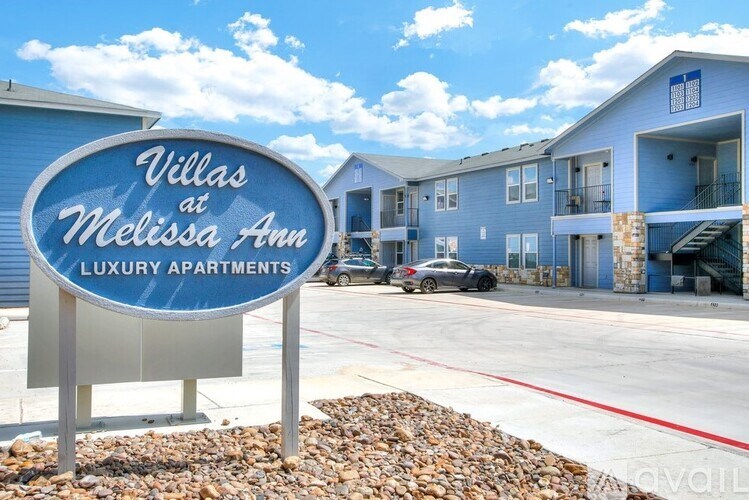 A sign for Villas at Melissa Ann Luxury Apartments stands in front of a building.