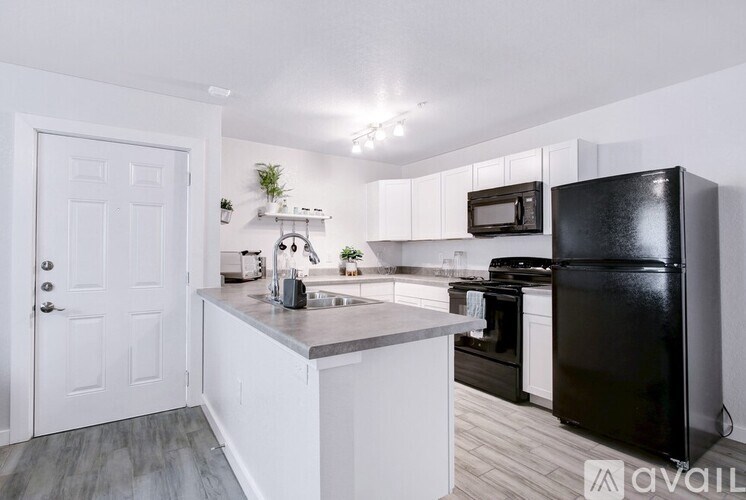 A kitchen with white cabinets and a black refrigerator.