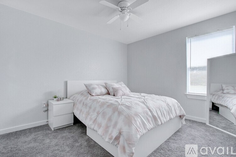 A bedroom with a bed, nightstand, and a fan.