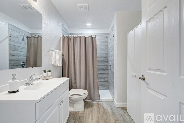 A bathroom with a white sink, toilet, and a shower with a brown curtain.