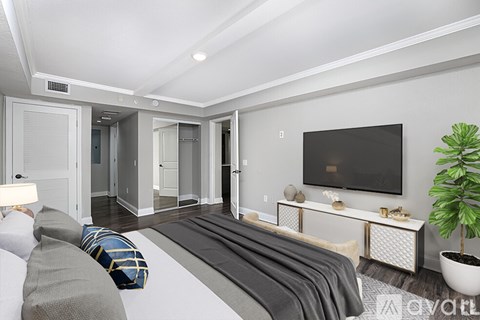 A living room with a grey couch and a television on the wall.