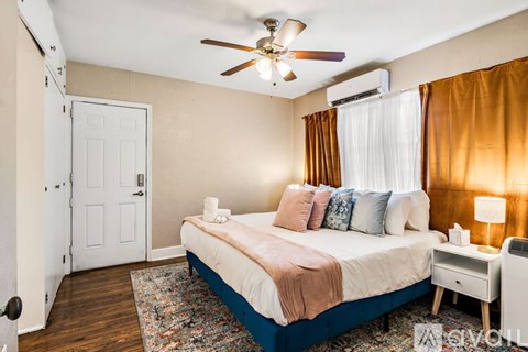 A bedroom with a bed, nightstand, and window with curtains.