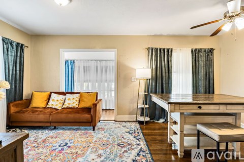 A living room with a brown couch, a wooden table, and a fan.