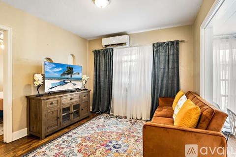 A living room with a television, a couch, and a rug.
