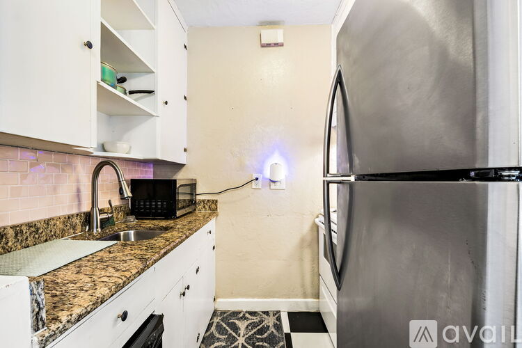 A kitchen with a granite countertop and a black refrigerator.