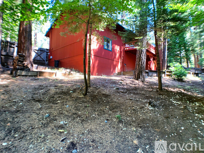 A red building is surrounded by trees in a wooded area.