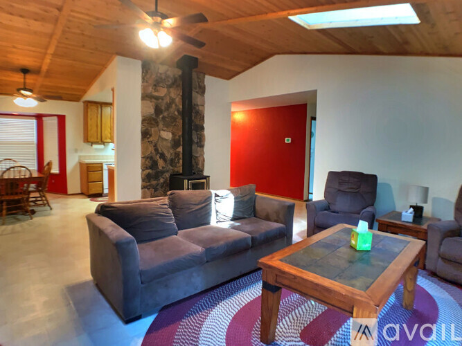 A living room with a grey couch, a wooden coffee table, and a red door.