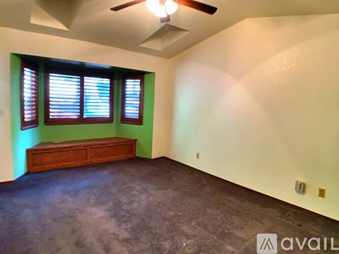 A room with a ceiling fan and a bench under a window.