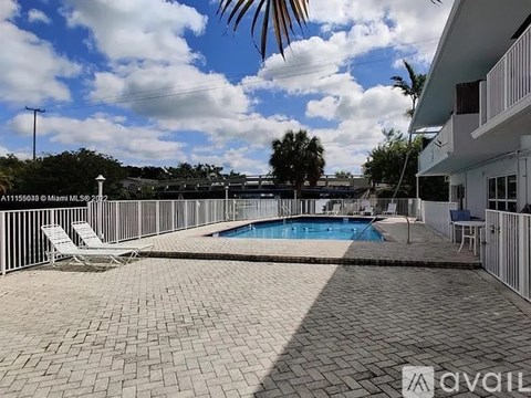 A pool surrounded by a patio and a white fence.
