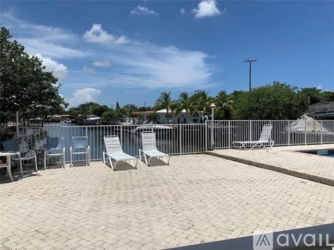 A sunny day at the pool with chairs and a fence.