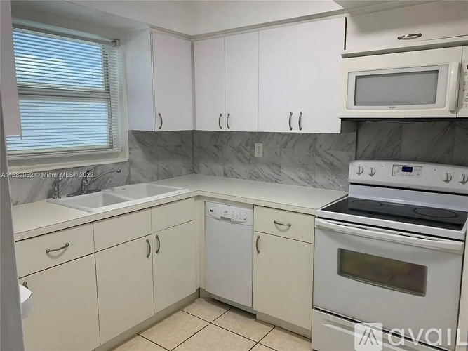 A kitchen with white cabinets and a marble backsplash.