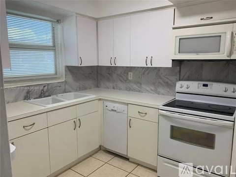 A kitchen with white cabinets and a marble backsplash.