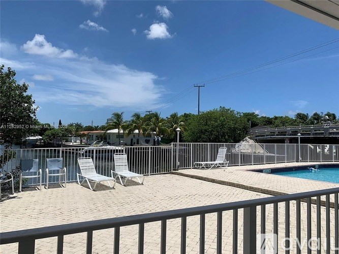 A pool area with chairs and a fence.
