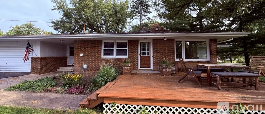 A patio with a table and chairs is surrounded by greenery.