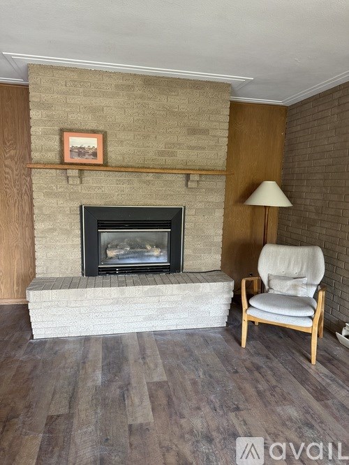 A fireplace with a picture above it and a chair to the side.