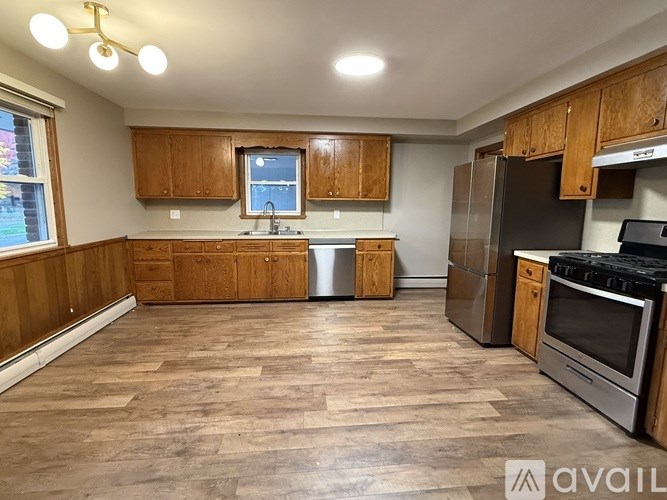A kitchen with wooden cabinets and a stainless steel refrigerator.