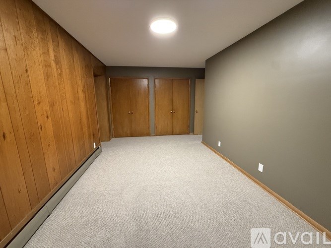A room with wooden walls and carpeted floor with two doors.