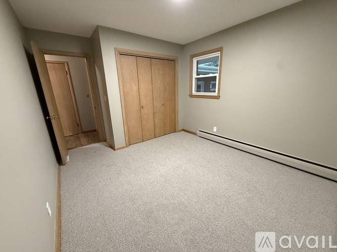 A room with carpeted floor, two doors, and a window.